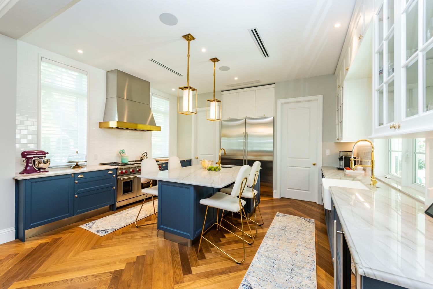 Renovated kitchen with blue cabinetry and herringbone wood floor