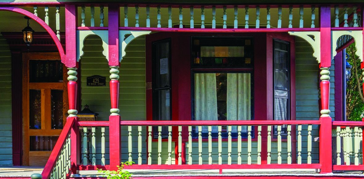 Detail of the restored Victorian porch with red spindles and green siding
