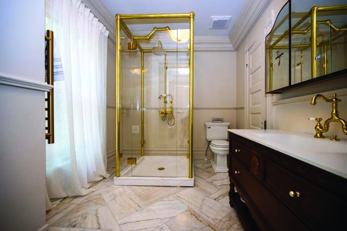 A freestanding shower with custom glass and brass, built on marble floors.